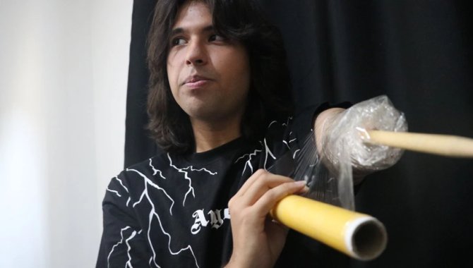 Depremde kolunun büyük bölümünü kaybeden genç, streç filmle sabitlediği bagetle bateri çalıyor