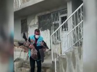 Sağlık çalışanı, yürümekte zorlanan yaşlı kadını kucağında taşıdı